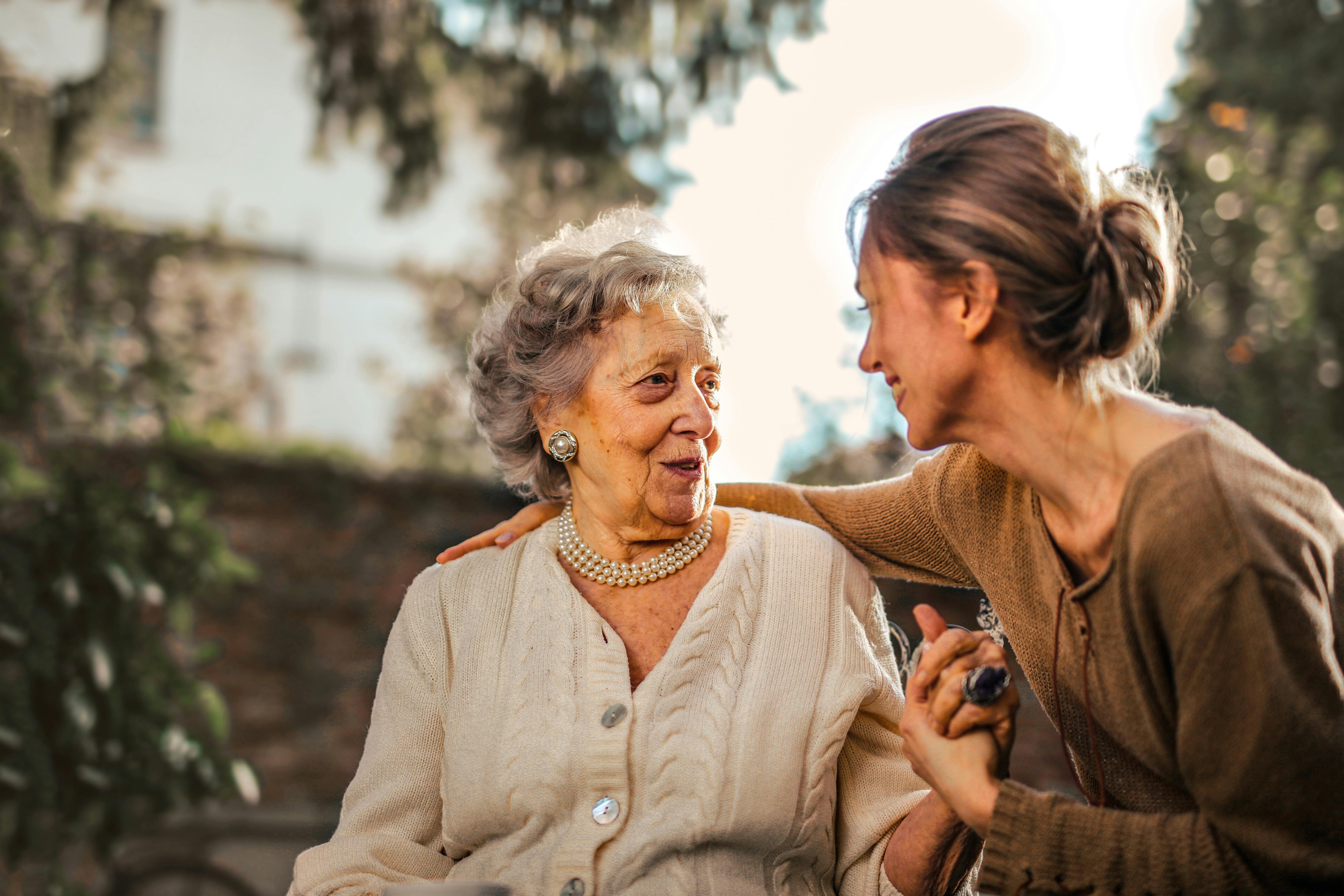 A senior woman and her adult daughter share a warm moment outdoors, illustrating the importance of organized family documents and end-of-life planning for busy moms and aging parents.